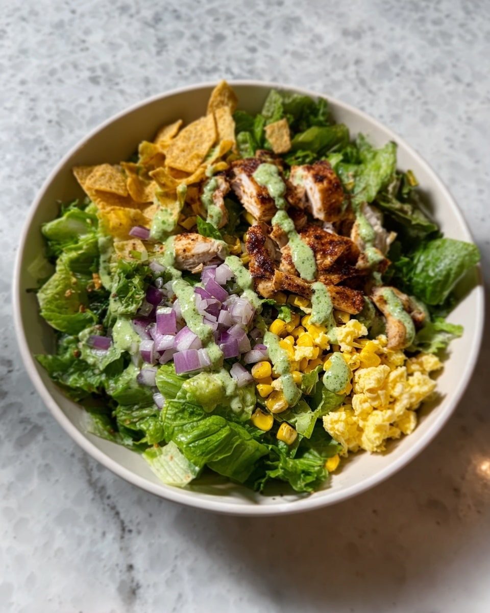 The image shows a white bowl filled with a fresh salad, placed on a white marbled surface. The bottom layer consists of leafy green lettuce, providing a vibrant base. On top, there is a layer of light yellow scrambled eggs covering part of the greens. Scattered over this are small purple diced onions, adding color contrast. Next to these, there are pieces of roasted corn kernels and some well-cooked brown chicken pieces, positioned on one side. The salad is topped with a drizzle of green sauce and garnished with a few whole tortilla chips. Photo taken with an iphone --ar 4:5 --v 7