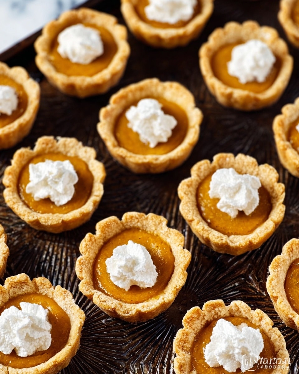 The image shows many small tartlets arranged closely on a dark baking tray with a textured pattern. Each tartlet has a golden-brown crust forming a shallow cup shape. Inside, a smooth and glossy orange filling sits evenly, topped with a small dollop of white whipped cream in the center. The tartlet shells look crisp and slightly crumbly around the edges. The contrast between the bright orange filling and white cream is clear, with each tartlet uniformly sized and shaped. The scene is simple and inviting, displayed on a white marbled surface. photo taken with an iphone --ar 4:5 --v 7