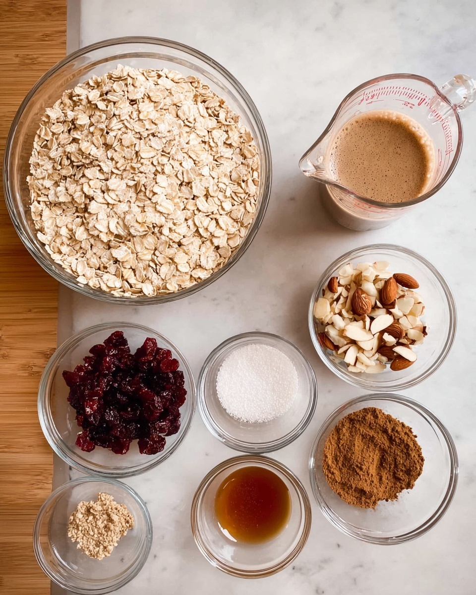 The image shows a clear large glass bowl filled with pale beige rolled oats on the left. To the right, there are eight small clear glass bowls and a clear glass measuring cup arranged on a white marbled surface. The measuring cup contains a frothy brown liquid. The small bowls hold various ingredients: one with dark red dried cranberries, one with roughly chopped almonds that are light brown with white centers, one with light brown powder, one with amber liquid, and three others with small amounts of white, dark brown, and cinnamon-colored powders. photo taken with an iphone --ar 4:5 --v 7