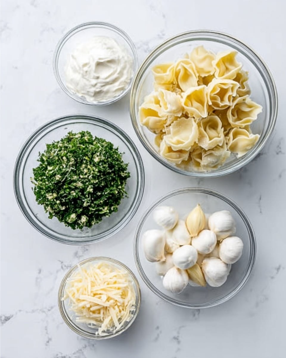The image shows five clear glass bowls placed on a white marbled surface. The largest bowl contains two sections: finely chopped green herbs on the left side and pale yellow, folded pasta shells on the right side. Surrounding this bowl are four smaller bowls: one with white sour cream, another with small white mozzarella balls, a third one filled with shredded pale yellow cheese, and the smallest bowl holding three cloves of garlic. The scene is clean and bright, with simple and fresh ingredients clearly visible. Photo taken with an iphone --ar 4:5 --v 7