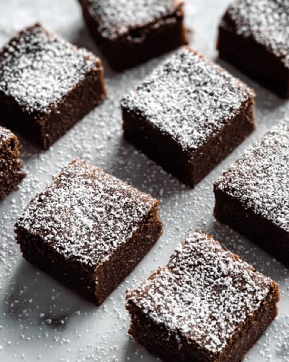 The image shows several small square brownies arranged on a white marbled surface. Each brownie is dark brown with a slightly rough texture on top, and they are dusted with a light layer of white powdered sugar. The brownies are placed close to each other but not stacked, creating a neat and tidy layout. The contrast between the dark chocolate color and the white powdered sugar gives a simple but appealing look. photo taken with an iphone --ar 4:5 --v 7