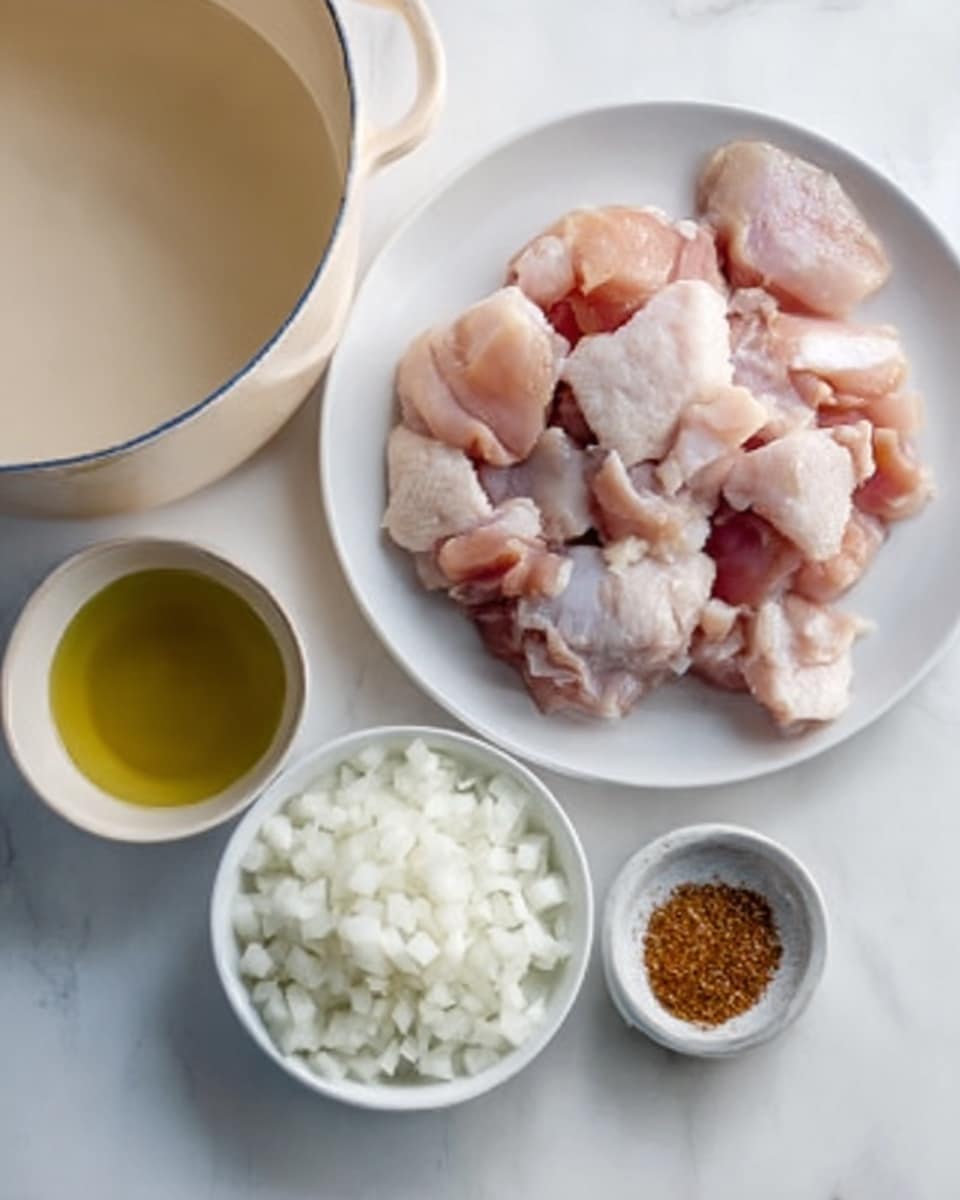 The image shows raw chicken pieces placed on a white plate, arranged in a loose pile. To the left, there is a cream-colored pot partially visible. Below the plate, there is a small white bowl filled with chopped white onions positioned closest to the bottom center. Next to the onions bowl is a small container with a greenish-yellow liquid, likely oil. To the right of the onions is a smaller white bowl containing a reddish-brown spice. The background is a white marbled surface. photo taken with an iphone --ar 4:5 --v 7