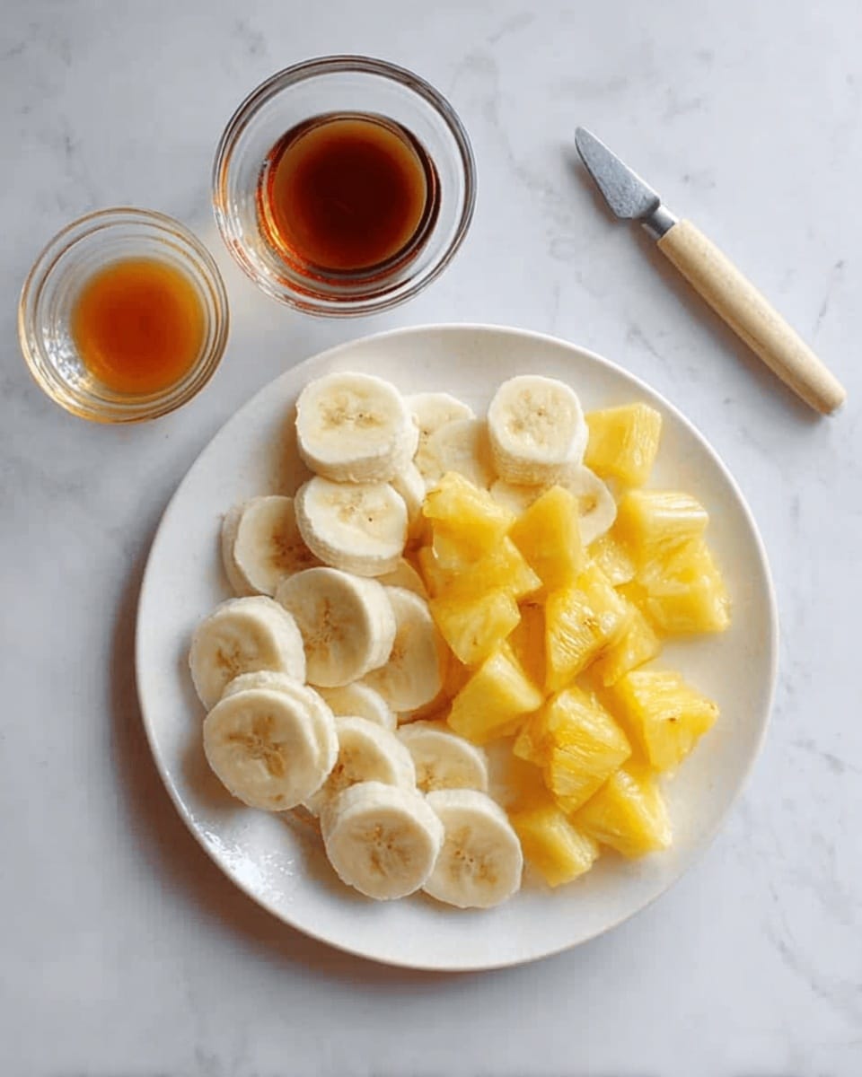 A white plate on a white marbled surface holds a simple fruit arrangement with three layers. The first layer, arranged around the edge, consists of peeled banana pieces with their smooth, creamy texture. The second layer fills the center with small pineapple chunks, bright yellow and juicy, giving a slightly rough texture. Beside the plate on the white marbled surface are two small transparent bowls, one containing a dark brown liquid and the other filled with a lighter brown syrupy liquid. A metal utensil with a light wooden handle lies near the top right side of the image. Photo taken with an iphone --ar 4:5 --v 7