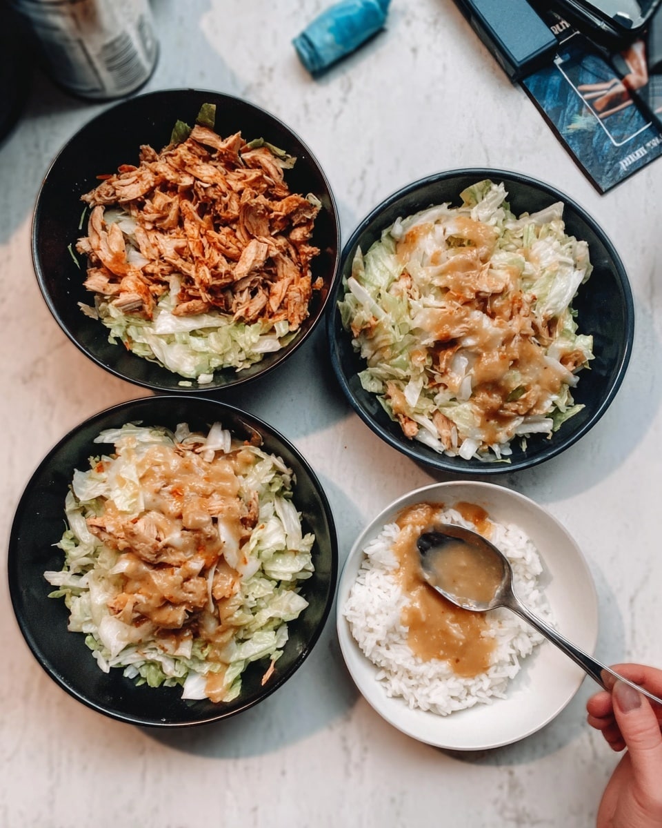 The image shows two black bowls filled with a mix of chopped cooked chicken and shredded cabbage or lettuce, both layers of the chicken and cabbage visible. Next to these bowls are two white plates containing white rice topped with a light brown sauce, placed on a white marbled surface. A woman's hand is holding a spoon near one of the plates. Photo taken with an iphone --ar 4:5 --v 7