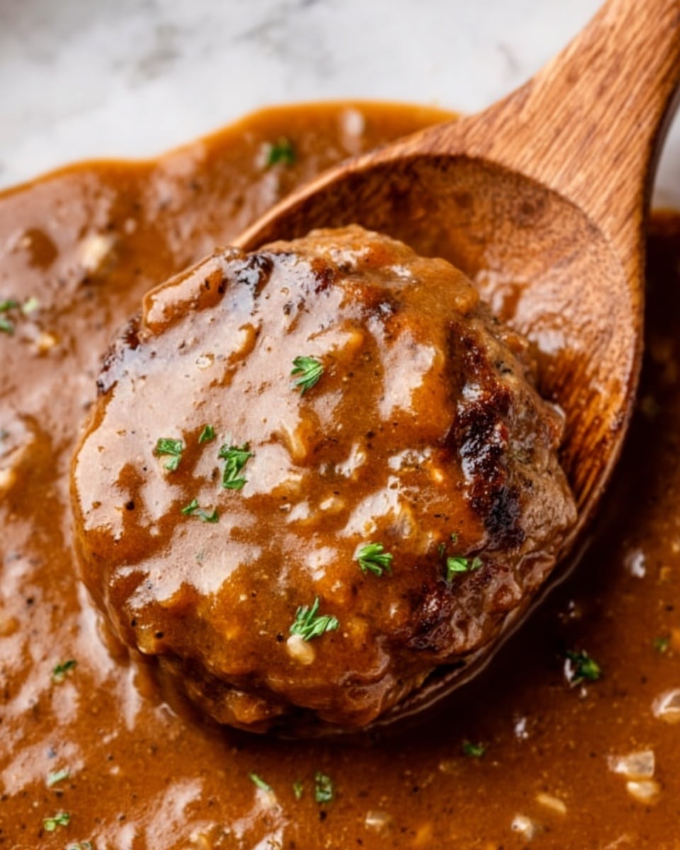 The image shows a thick, round patty covered with rich brown gravy that has a glossy texture and small bits throughout. The patty is at the center of the wooden spoon, with the thick gravy spreading around it, filling the spoon and slightly overflowing. Small green herbs are sprinkled on top of the patty, adding a touch of color to the brown tones. The background is a white marbled texture. Photo taken with an iphone --ar 4:5 --v 7