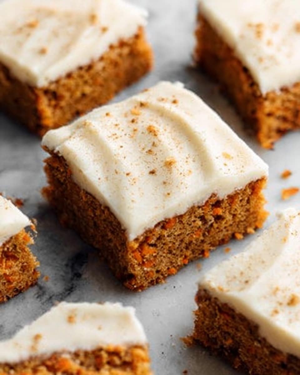 The image shows close-up square pieces of carrot cake with a thick, creamy white frosting layer on top. The carrot cake layer is a warm orange-brown color with a moist texture. Small bits of grated carrot and spices are visible inside the cake. The frosting is smooth with slight swirl marks and is topped with a few light brown specks of spice, likely cinnamon or nutmeg. The cake pieces are arranged on a white marbled surface, with one piece slightly separated from the others to show its side and top clearly. Photo taken with an iphone --ar 4:5 --v 7