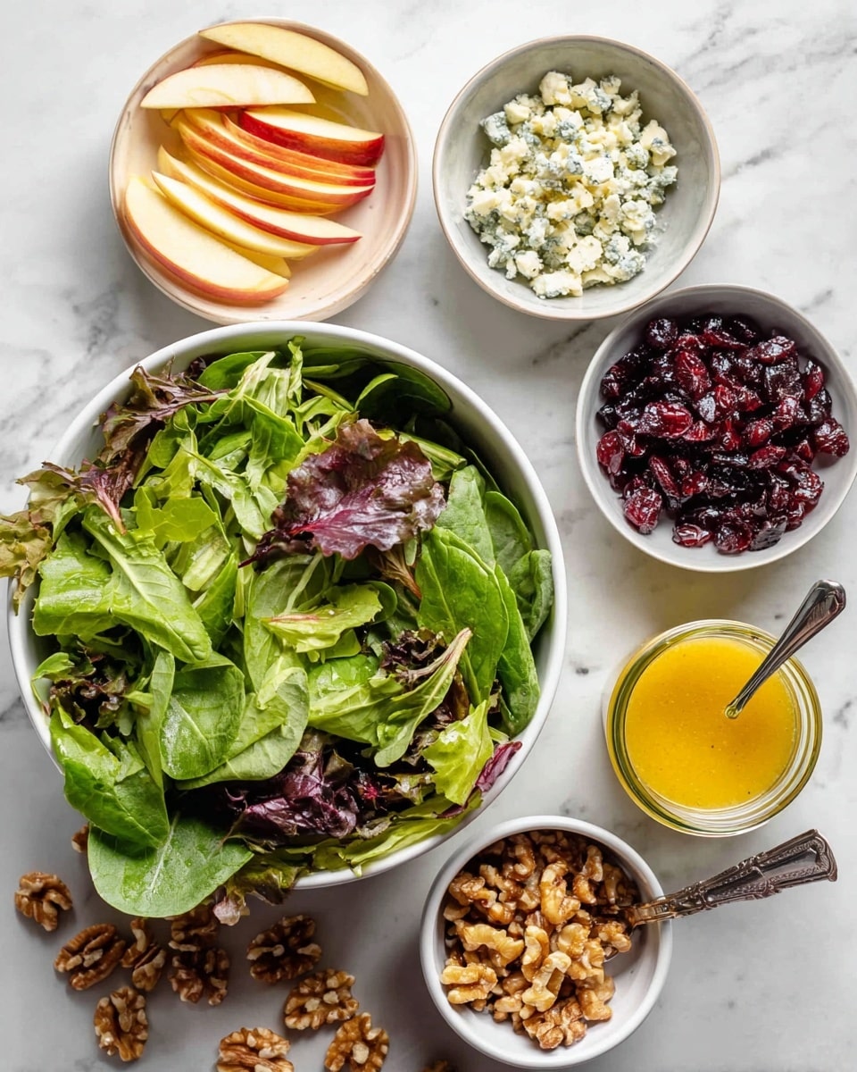 A top view of a salad preparation setup on a white marbled surface, showing one large white bowl filled with fresh leafy greens featuring different shades of green and purple, including spinach and red leaf lettuce. Surrounding this bowl are five smaller white bowls: one with thinly sliced apple pieces showing yellow and red skin, one with dried dark red cranberries, one with crumbled white and blue cheese, one with chopped light brown walnuts, and one clear jar containing a bright yellow mustard dressing with a small silver spoon inside. Scattered walnut pieces are seen on the surface near the bowls. photo taken with an iphone --ar 4:5 --v 7