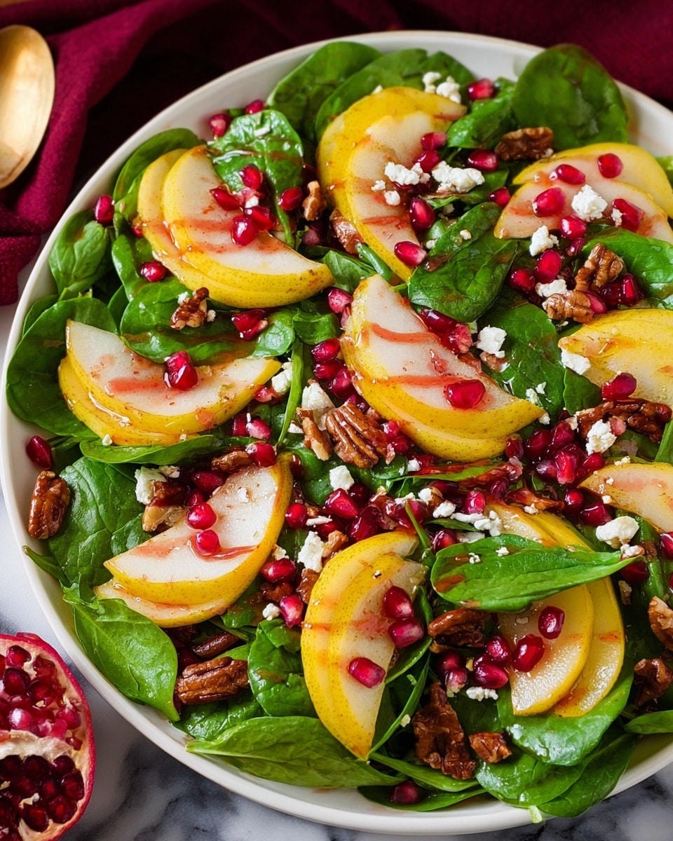 A white plate filled with a colorful salad showing several layers: bright green spinach leaves form the base layer, topped with golden yellow pear slices layered evenly on top. Scattered across the salad are deep red pomegranate seeds adding a bright contrast. Small pieces of white cheese are spread throughout the salad, along with a sprinkling of light brown pecan halves. A glossy red dressing is drizzled over the entire dish. The plate sits on a white marbled surface with a dark red cloth in the background. photo taken with an iphone --ar 4:5 --v 7