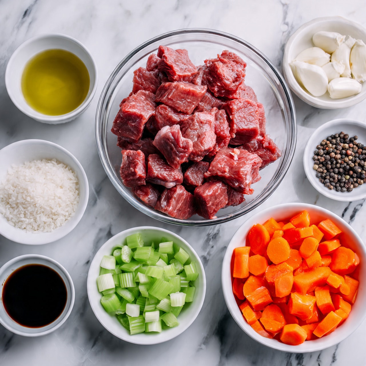 The image shows several clear glass bowls and small white bowls arranged on a white marbled surface. In the center, there is a large clear glass bowl filled with raw red meat chunks. Around it, smaller bowls hold sliced bright orange carrots, chopped green celery, chopped white onions, white grains, a dark brown sauce, light yellow oil, chopped garlic, and whole black peppercorns. All the ingredients are clean and neatly placed, ready for cooking. photo taken with an iphone --ar 4:5 --v 7