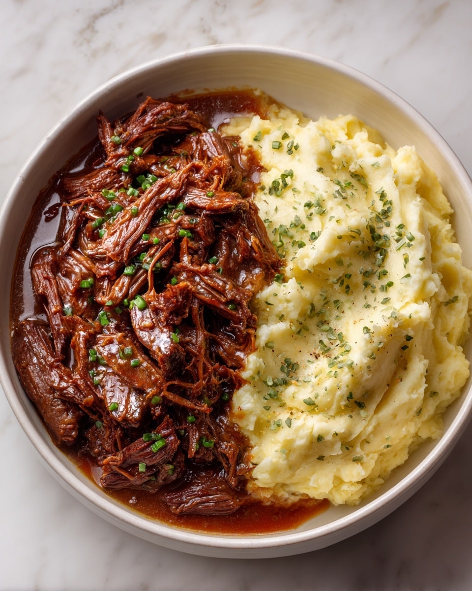 The dish shows two thick layers: on the left side, there is shredded dark brown beef with a glossy texture, coated in a rich brown sauce and garnished with small green herb pieces scattered on top; on the right side, there is a scoop of creamy, light beige mashed potatoes with a slightly rough surface and small green herb specks, resting beside the beef. All of this is served in a white bowl placed on a white marbled surface. photo taken with an iphone --ar 4:5 --v 7