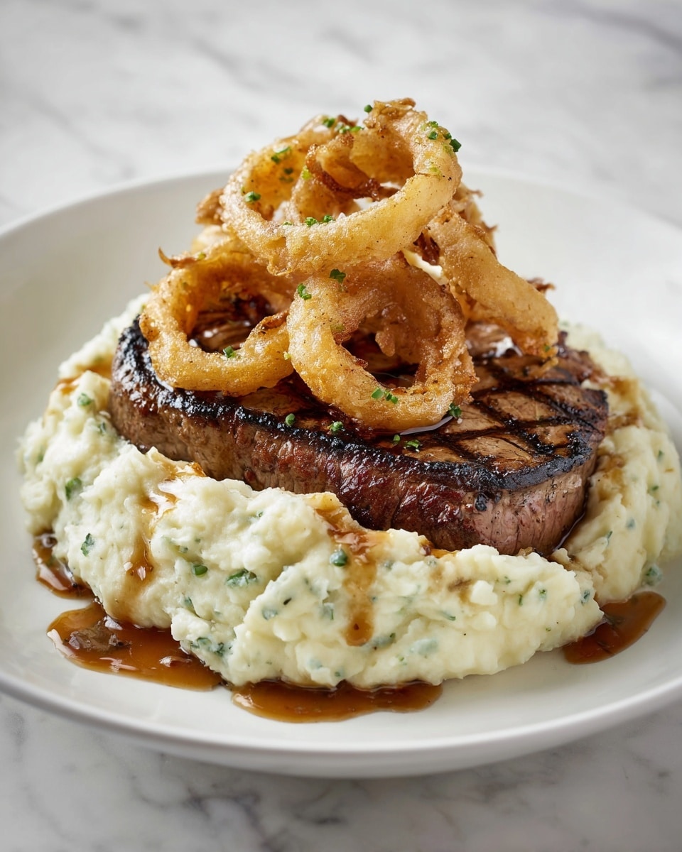 A grilled steak with visible char marks is placed on top of a thick, creamy layer of mashed potatoes with small green herb pieces mixed in. On top of the steak, there are several golden-brown caramelized onion rings, some glistening with a shiny sauce that is also drizzled around the steak and mashed potatoes. The dish is presented on a white plate, all set against a white marbled surface. The overall look is warm, rich, and inviting, with a good balance of textures and colors, photo taken with an iphone --ar 4:5 --v 7