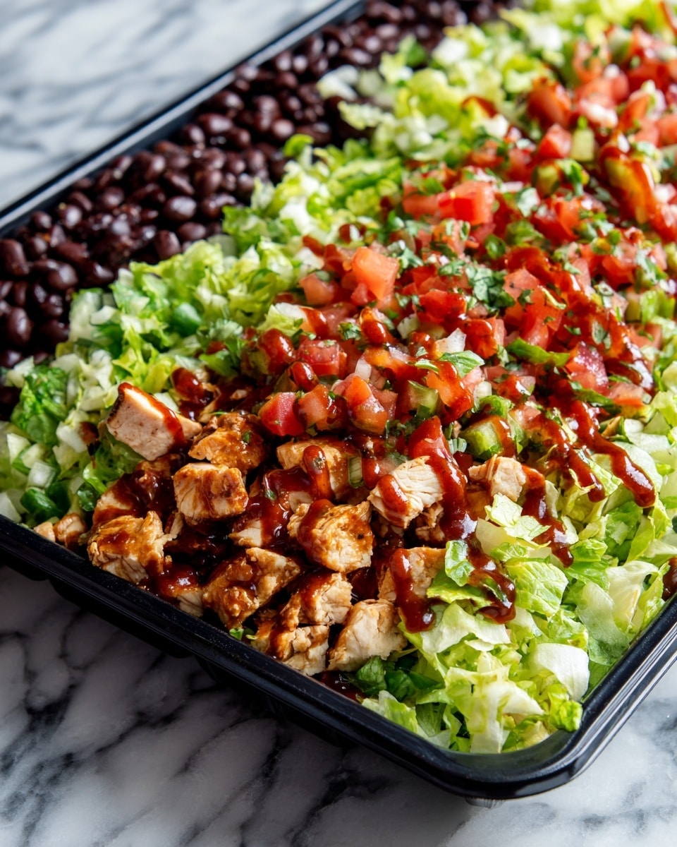 A close-up view of a black tray filled with a colorful salad. The bottom layer has dark black beans spread evenly. On top of the beans is a layer of chopped light green lettuce. There are small pieces of light brown chicken scattered above the lettuce. Over the chicken and lettuce, there are red and green diced tomatoes and herbs, adding a bright and fresh mix of colors. The whole salad is covered with a reddish-brown sauce drizzled generously across the top. The tray sits on a white marbled surface. Photo taken with an iphone --ar 4:5 --v 7
