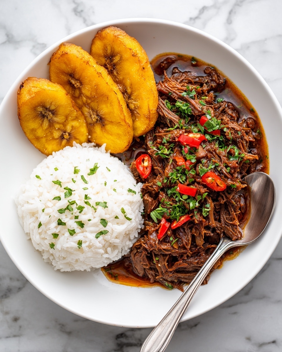 The dish is served on a white plate with three sections: on the left, there are three golden fried plantain slices with a slightly crispy texture; in the middle bottom, there is a portion of fluffy white rice garnished with small green herbs; on the right side, there is a rich, dark brown shredded meat stew with visible red pepper slices and sprinkled with fresh green herbs on top. A silver spoon rests at the bottom right of the plate. The plate is placed on a white marbled surface. Photo taken with an iphone --ar 4:5 --v 7