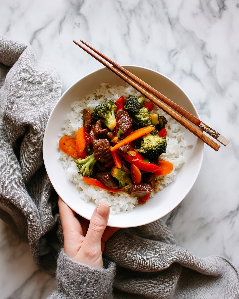 A white bowl filled with a bed of white rice serves as the base layer. On top, there is a colorful mix of stir-fried vegetables and small pieces of meat, arranged evenly across the rice. The vegetables include bright orange carrots, green broccoli, and red bell peppers, with a slight shine from the sauce. The meat pieces are brown and look tender. A pair of wooden chopsticks rest on the edge of the bowl, held by a woman’s hand above the food. The bowl is placed on a white marbled surface, with a grey cloth napkin beside it. photo taken with an iphone --ar 4:5 --v 7