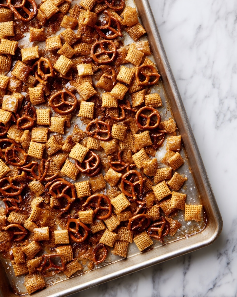 The image shows a metal baking tray filled with a single layer of small, square-shaped snacks that are light brown with a shiny, sugary coating. Scattered evenly on top are pieces of pretzels, darker brown in color and twisted in shape, creating a rough texture contrast with the smooth snacks underneath. The tray is placed on a surface with a white marbled texture. Photo taken with an iphone --ar 4:5 --v 7