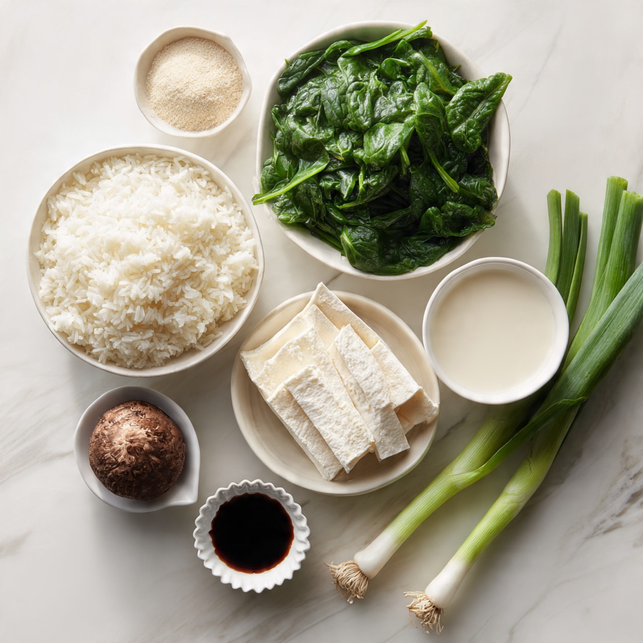 The image shows seven white bowls and dishes arranged on a white marbled surface. The largest bowl at the center contains fluffy white rice. Above it, a bowl is full of fresh green spinach leaves with smooth textures and slightly shiny surfaces. To the right of the spinach, there is a bowl filled with a creamy white liquid, smooth in texture. To the left of the rice, a small dish holds a fine beige powder. Below the powder, a bowl contains pale, thin, soft-looking tofu sheets layered loosely. Below the rice, a small white dish holds a dark brown, round mushroom with a crinkled texture. At the bottom center is a small white scalloped dish filled with dark soy sauce. To the right side, two long green onions lie on the white marbled surface, showing different shades of green with smooth, shiny textures. photo taken with an iphone --ar 4:5 --v 7