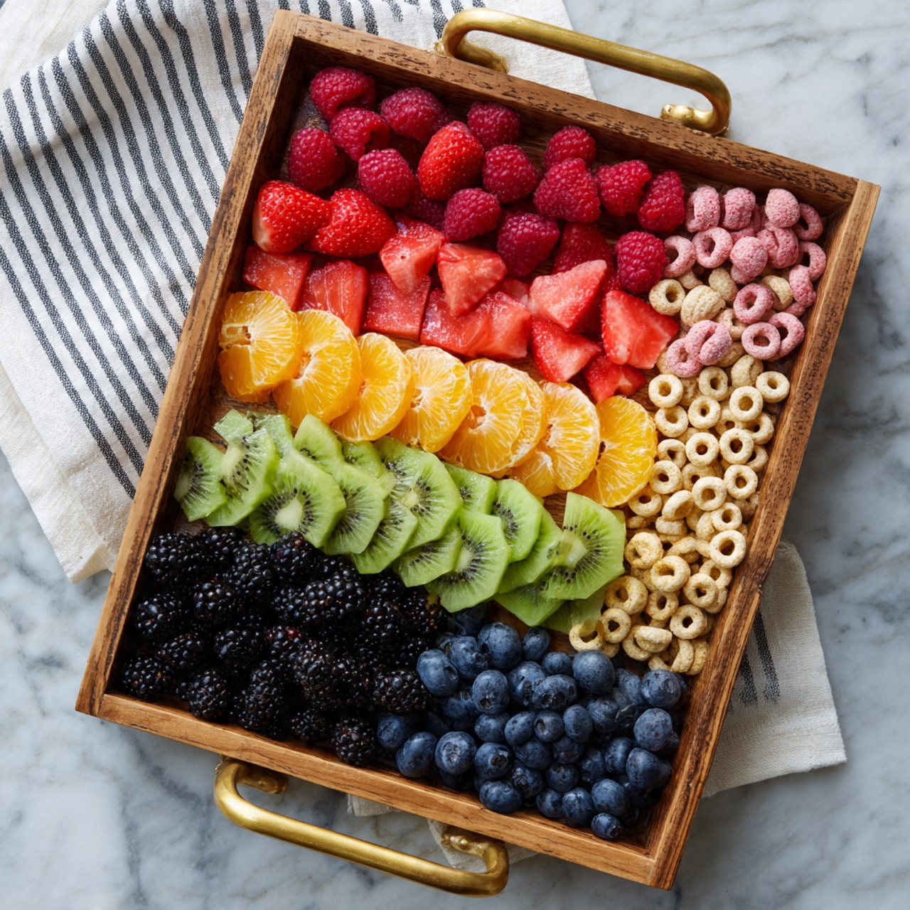 A wooden tray with golden handles is filled with eight neat horizontal layers of food on a white marbled surface with a white and grey striped cloth nearby. From top to bottom, the first layer is red strawberries cut in halves and quarters, the second layer is red raspberries, the third layer is pinkish-red watermelon chunks, the fourth layer is bright orange peeled mandarin segments, the fifth layer is yellow pineapple chunks, the sixth layer is green sliced kiwi, the seventh layer is dark blue blueberries, the eighth layer is black blackberries, the ninth layer is light pink small round candies, and the tenth layer is light tan cereal loops with colorful marshmallow pieces mixed in. photo taken with an iphone --ar 4:5 --v 7