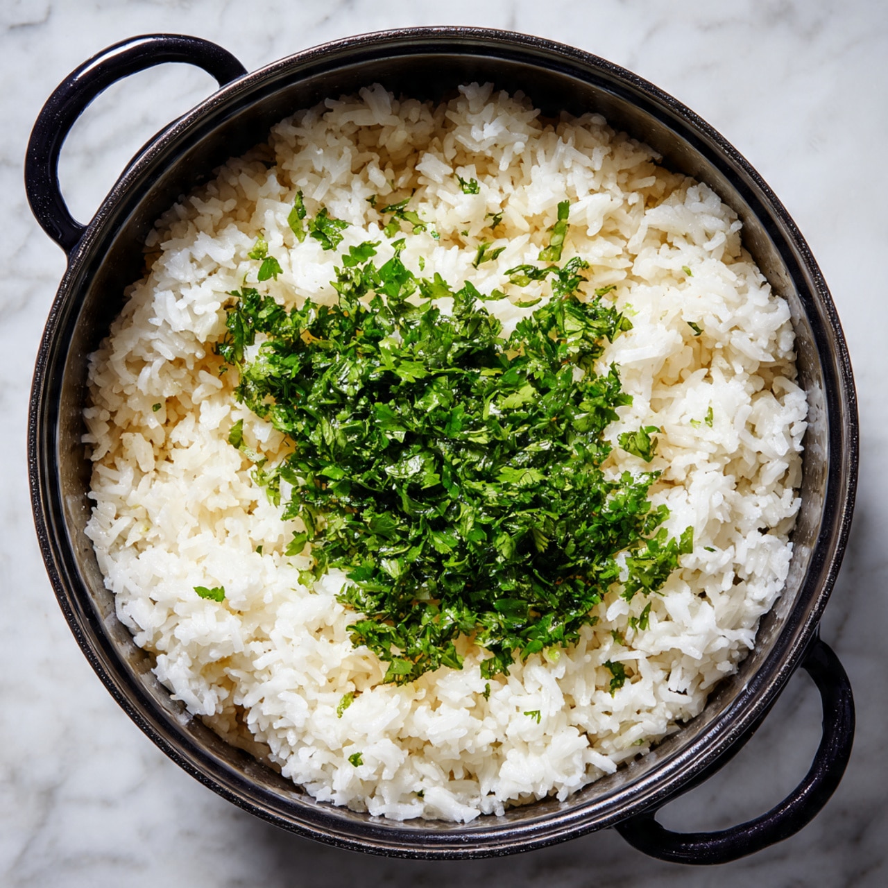 The image shows a black pot filled with cooked white rice topped with a pile of finely chopped bright green herbs, likely cilantro or parsley, scattered evenly in the center. The rice grains look soft and slightly sticky, with the green herbs adding a fresh, vibrant contrast on top. The pot handles are visible, and the light highlights the textures of the rice and herbs well, creating a warm and appetizing appearance. The background is a white marbled texture. photo taken with an iphone --ar 4:5 --v 7