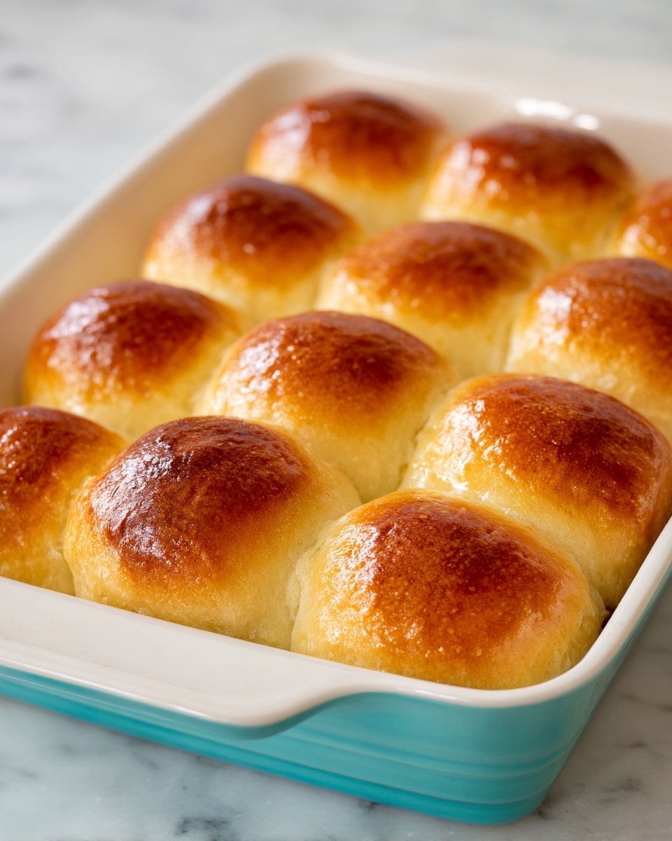 The image shows a long braided bread with a shiny, golden-brown crust. The braid is thick and made of three large strands tightly woven together, creating a smooth, glossy texture on top. The bread rests on a white marbled surface, highlighting its warm color and soft inside that is just visible at the ends. Photo taken with an iphone --ar 4:5 --v 7