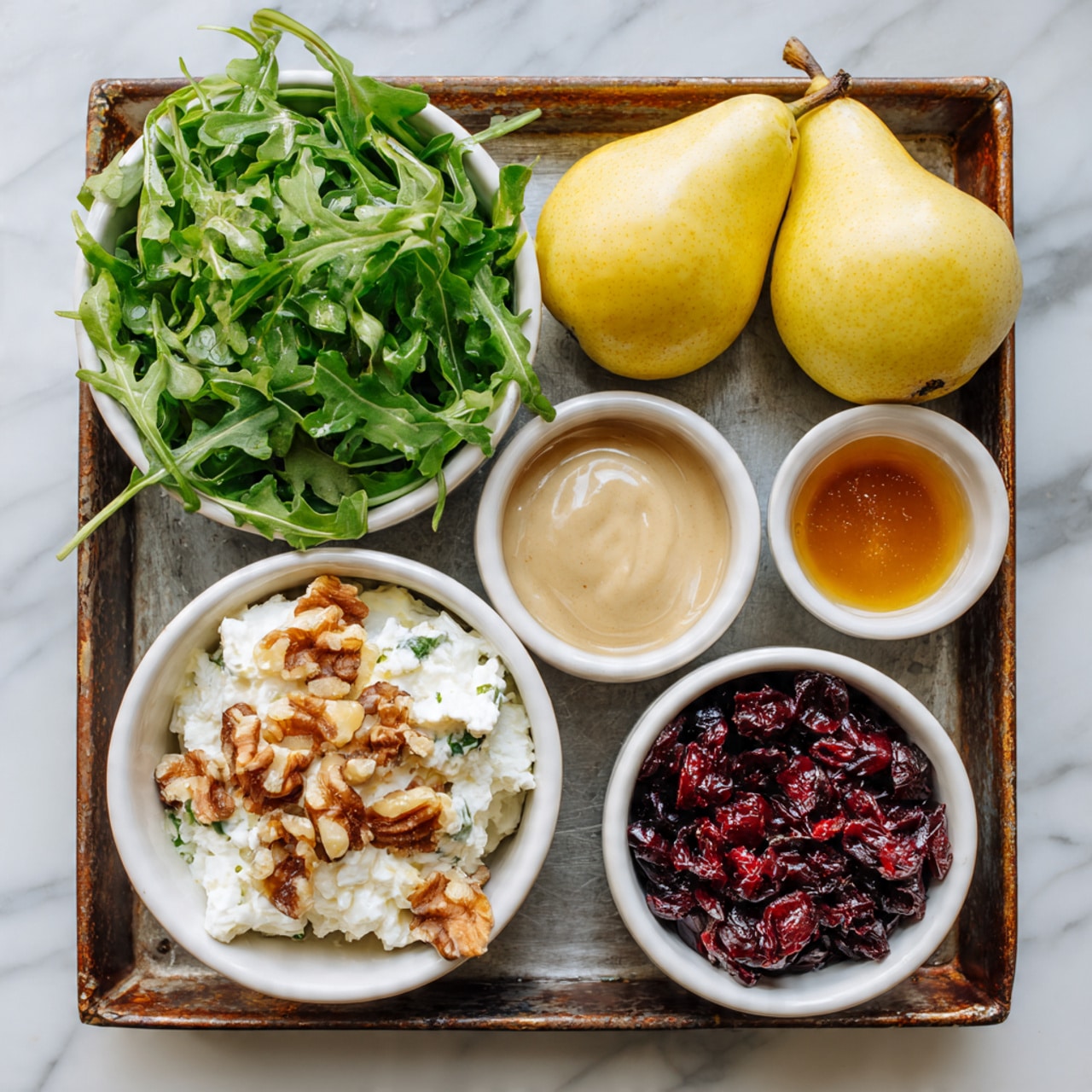 The image shows a rusty metal tray on a white marbled surface, holding five small white bowls and two yellow pears. The top left bowl is filled with fresh green arugula leaves. Below the arugula, the bowl has white creamy cheese with light brown nuts mixed in. To the right of the cheese, a bowl contains red dried cranberries. Above the cranberries, there is a light brown mustard sauce in a bowl. Next to the mustard, the bowl has a light brown honey-like liquid. The top left corner of the tray has two yellow pears side by side. The photo taken with an iphone --ar 4:5 --v 7