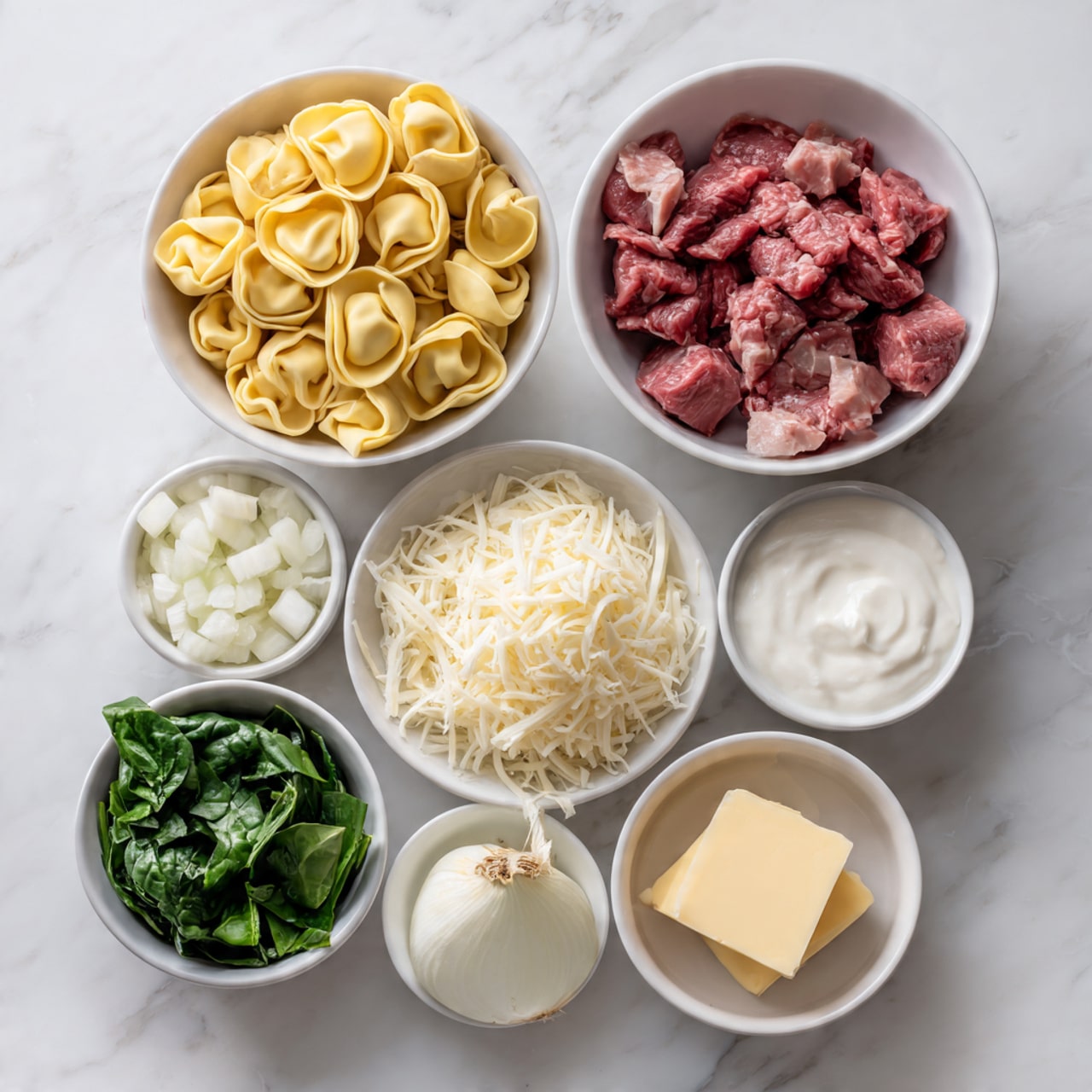 The image shows seven white bowls arranged on a white marbled surface, each holding a different ingredient. One large bowl contains yellow tortellini pasta, another large bowl is filled with small chunks of red meat. A small bowl has shredded white cheese, another small bowl holds green leafy vegetables, possibly spinach or basil. There is a small bowl with chopped white onion, one small bowl with white cream or milk, and a small dish with a square piece of pale yellow butter. The ingredients are neatly placed and clearly separated. Photo taken with an iphone --ar 4:5 --v 7