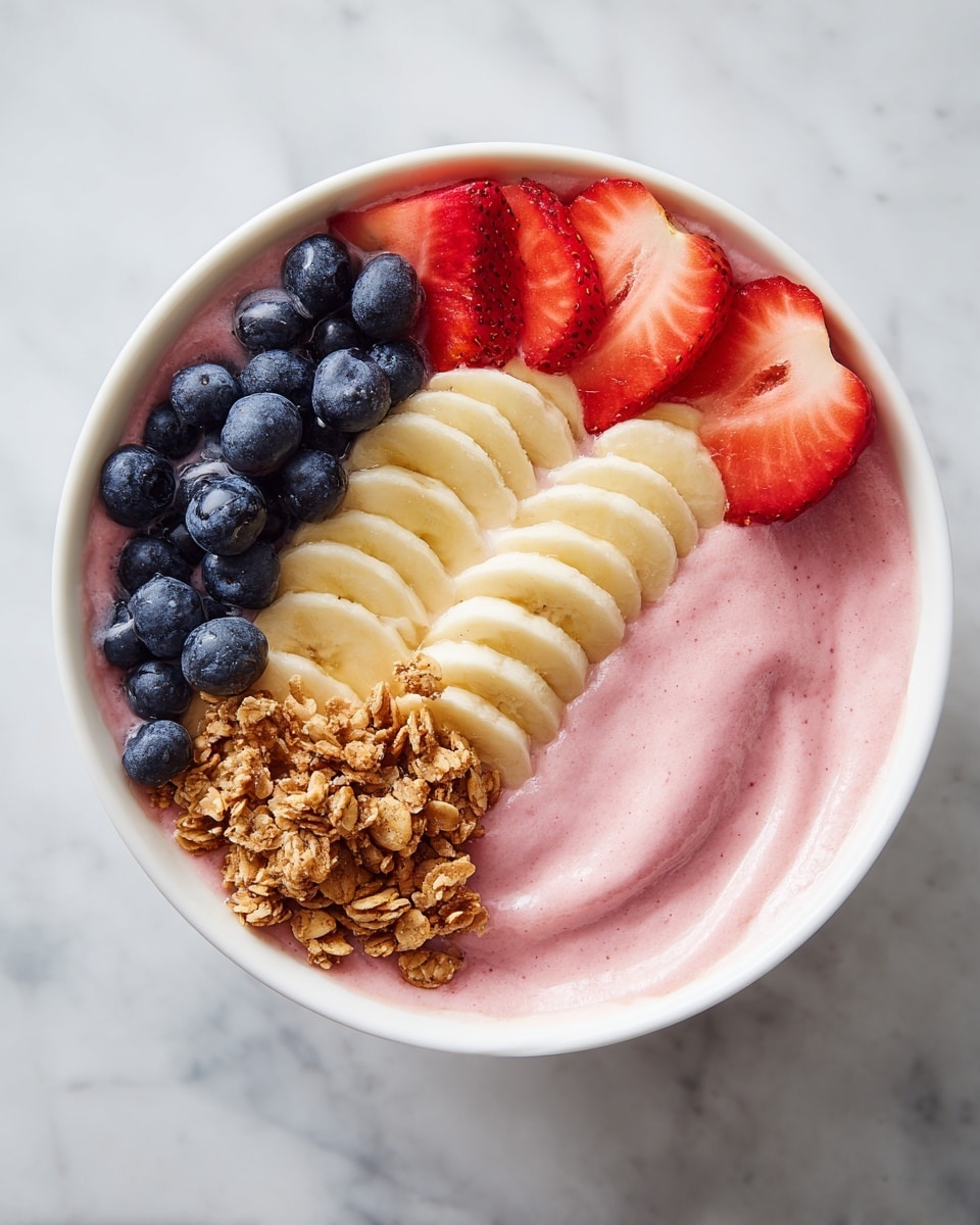 A white bowl is filled with a thick, creamy pink smoothie base that has a smooth, slightly swirled texture. On top, there are fresh fruit and granola arranged in four sections: at the bottom, a row of evenly sliced pale yellow banana pieces; on the left, a small cluster of plump, dark blue blueberries; at the top right, layered bright red sliced strawberries; and next to them, a pile of light brown crunchy granola. The bowl sits on a white marbled surface. photo taken with an iphone --ar 4:5 --v 7