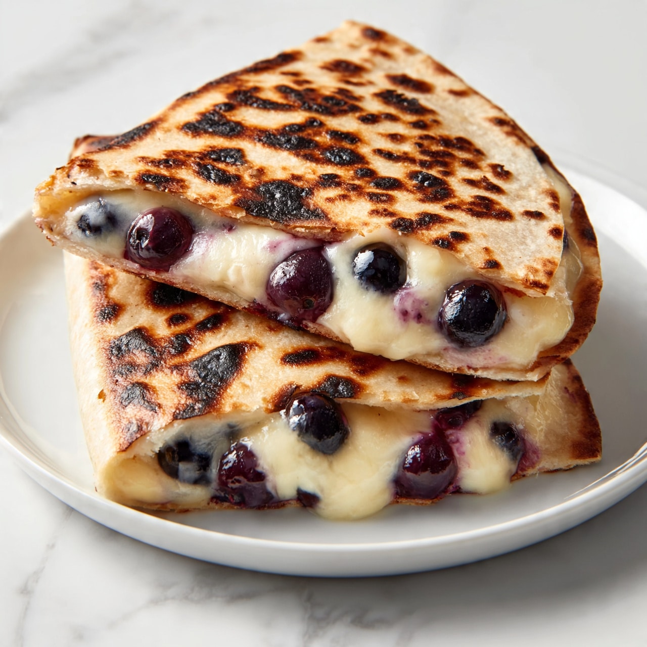 square image The image shows two folded quesadillas stacked on top of each other on a white plate, placed on a white marbled surface. The quesadillas have a golden brown, slightly charred outside with visible dark spots from grilling. Inside, a thick layer of melted cheese is mixed with whole, plump blueberries that give a rich purple color contrast to the creamy cheese. The edges of the quesadillas are slightly crisp while the melted cheese and blueberries inside look soft and juicy. The light highlights the textures of the toasted tortilla and the juicy filling. photo taken with an iphone --ar 4:5 --v 7