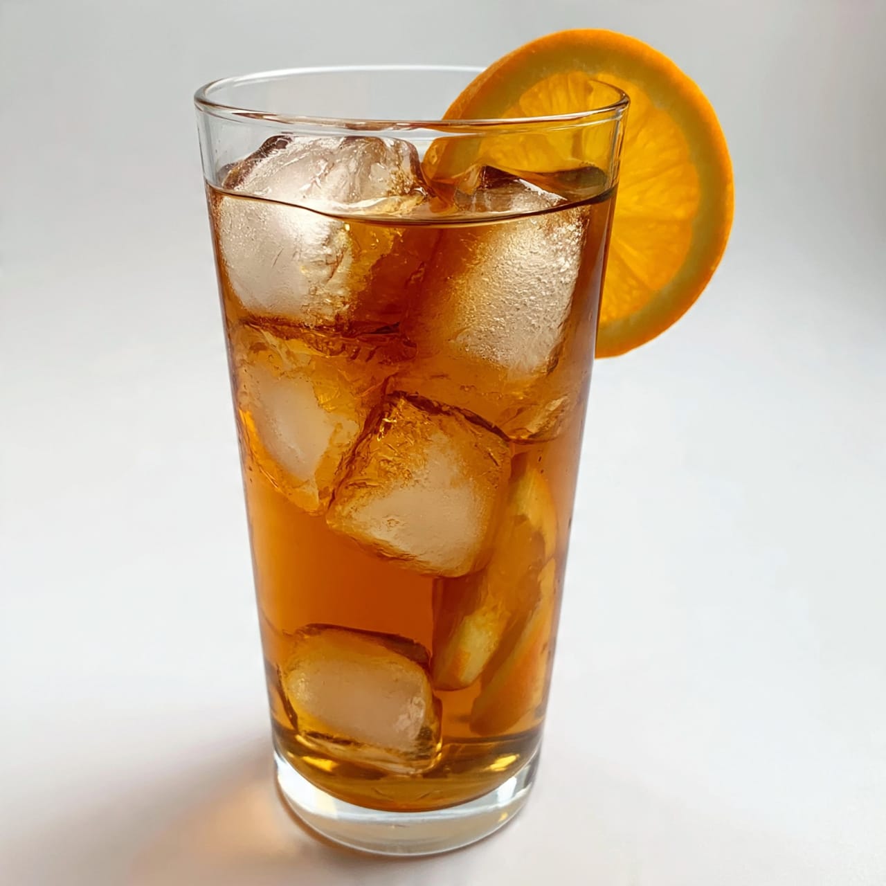 square image A tall clear glass filled with dark brown iced tea and ice cubes, with a thin yellow straw inside. On top of the glass, there are two green lime wedges placed on the rim. The glass is sitting on a wooden coaster, and there are a few light brown sugar cubes next to it on a white marbled surface. The background shows a blurred window with soft light coming through. photo taken with an iphone --ar 4:5 --v 7