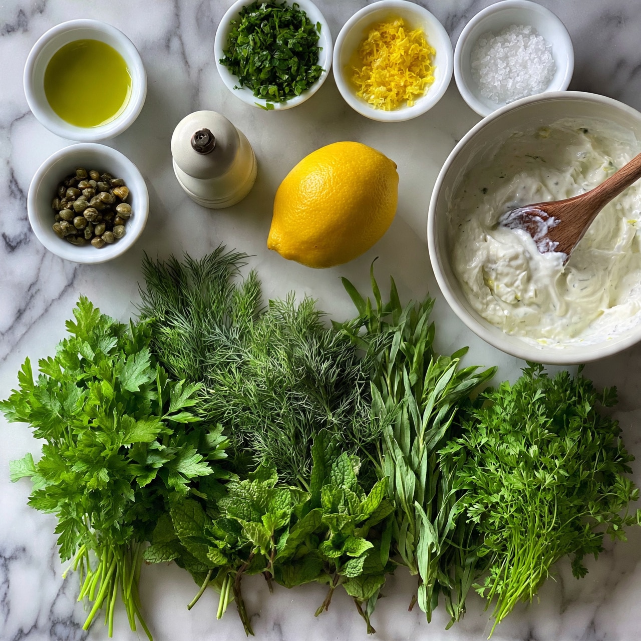 square image The image shows a white marbled surface with a collection of fresh green herbs including parsley, dill, mint, tarragon, and chervil spread out at the bottom. At the top are small white bowls holding olive oil, capers, chopped green herbs, lemon zest, and coarse salt. A whole yellow lemon sits in the center near a pepper grinder. On the right side, there is a white bowl with creamy white sauce being stirred with a wooden spoon. The colors are fresh and vibrant, with green tones contrasting against the white marbled background and bowls. photo taken with an iphone --ar 4:5 --v 7