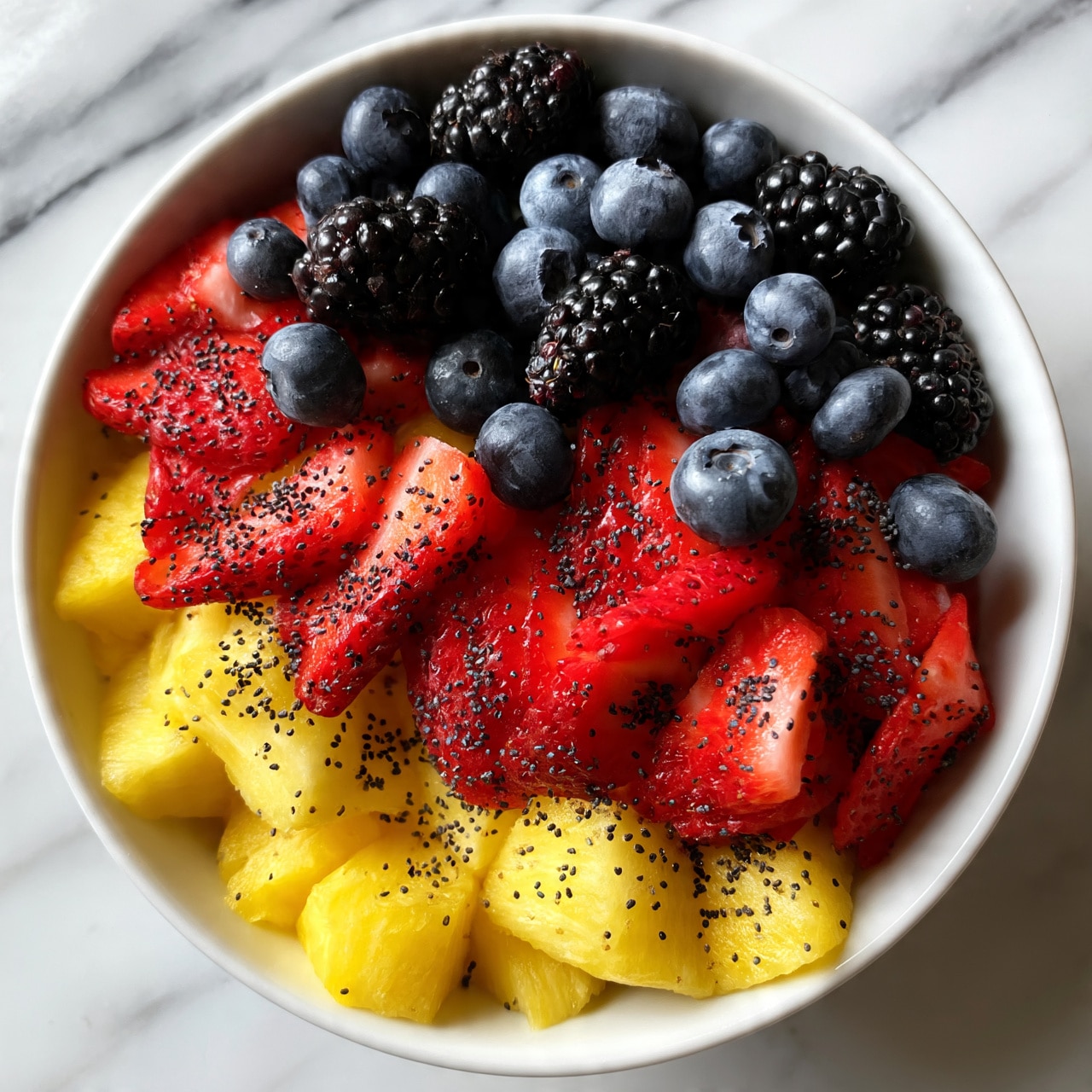 square image A white bowl filled with a colorful mix of fresh fruits. The bottom layer has bright yellow pineapple chunks spread evenly. On top of that, vibrant red strawberries sliced into pieces cover most of the bowl. Scattered throughout and above the strawberries are deep blue blueberries and blackberries, adding a rich contrast. Tiny black poppy seeds are sprinkled evenly across all the fruit, giving a speckled texture. The bowl sits on a white marbled surface. photo taken with an iphone --ar 4:5 --v 7