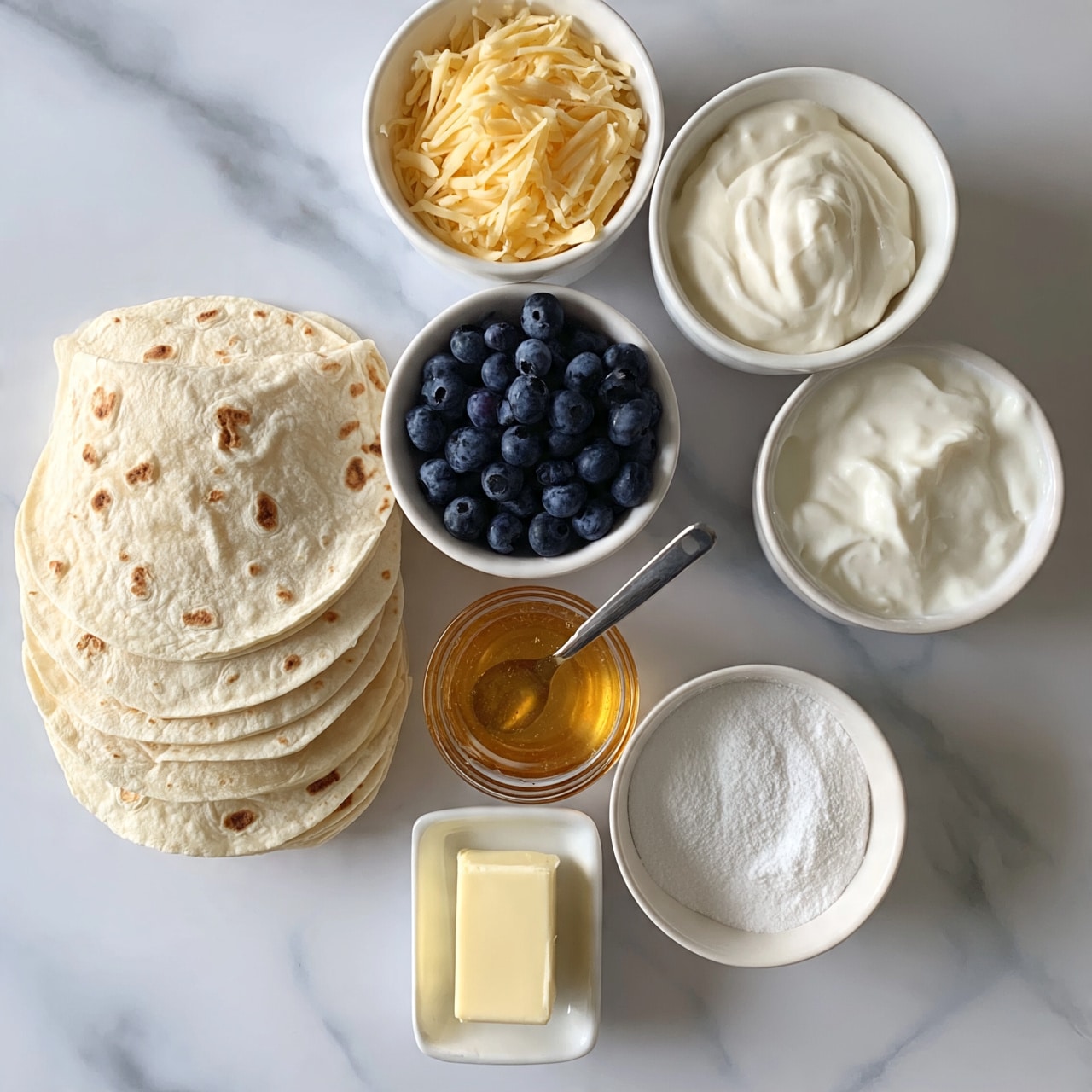 square image The image shows several ingredients laid out neatly on a white marbled surface. On the left, there is a stack of about eight light beige tortillas with small brown spots. To the right of the tortillas, there is a white bowl filled with fresh dark blue blueberries. Next to the blueberries, a small clear glass bowl contains golden honey with a spoon resting inside it. Below the honey, a small white butter dish holds a rectangular piece of pale yellow butter. To the right of the butter, a white bowl is filled with a fine white powder, likely sugar or flour. Above that, another white bowl contains a pile of shredded light yellow cheese. To the right of the powder, a final white bowl holds a creamy white substance, smooth in texture, possibly yogurt or sour cream. photo taken with an iphone --ar 4:5 --v 7