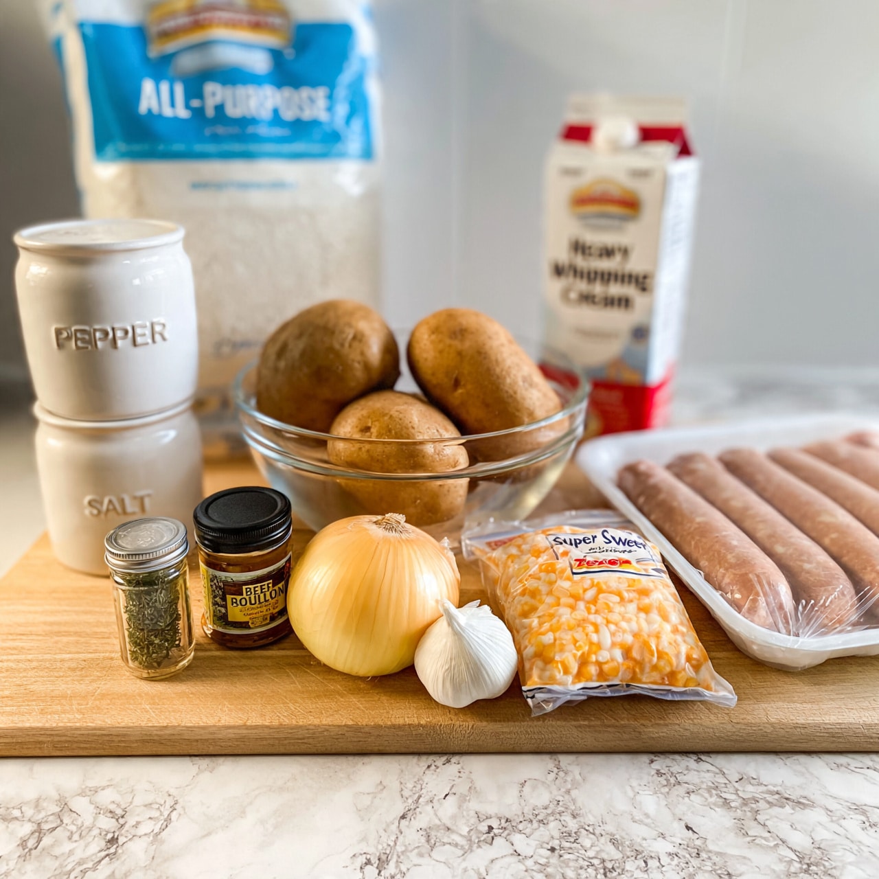 square image A collection of raw ingredients arranged on a light wooden surface with a white marbled texture background: a white ceramic container labeled pepper stacked on top of a similar container labeled salt on the left, a blue and white bag of all-purpose flour behind them; a clear glass bowl holding three brown potatoes in the center; a carton of heavy whipping cream with red and white colors on the right; in front of the potatoes, a small glass spice jar labeled thyme, a small black and yellow jar of beef bouillon, a whole yellow onion, a head of garlic, a bag of frozen super sweet corn with orange and white colors, and on the far right a white tray holding four raw bratwurst sausages in packaging. photo taken with an iphone --ar 4:5 --v 7
