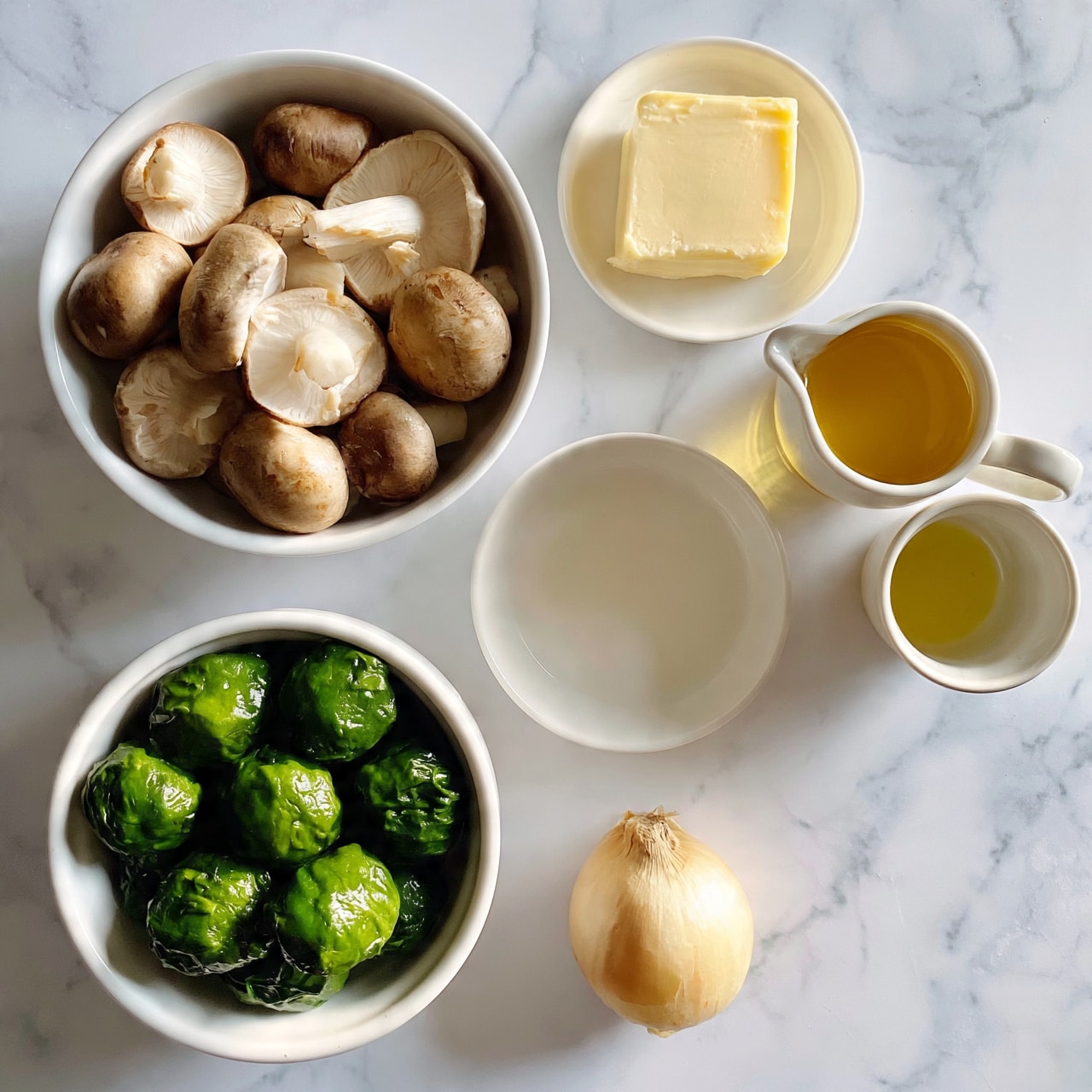square image The image shows five white bowls and plates arranged on a white marbled surface. At the bottom left, a white bowl holds bright green round balls of cooked spinach, looking smooth and moist. Above that, a white bowl is filled with whole brown mushrooms with pale undersides and white stems, showing a natural, firm texture. To the right near the top, a small white plate carries a square block of pale yellow butter with a smooth surface. Next to that, a pouring jug is filled with a golden-yellow liquid and another small cup has some light yellow oil. Below all bowls, a single unpeeled onion with a beige outer skin lies on the surface. The photo taken with an iphone --ar 4:5 --v 7