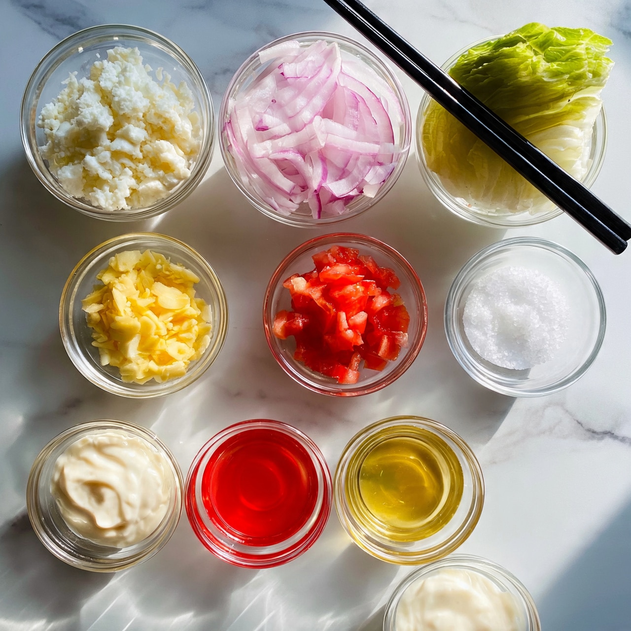 square image The image shows several small clear glass bowls arranged on a white marbled surface. The top row has three bowls: one with white crumbled cheese, one with thinly sliced red onions, and a wedge of green lettuce placed on two black chopsticks. Below these, from left to right, there is a small bowl with chopped yellow garlic, a small bowl with finely chopped red tomatoes, and a small bowl with white salt. In the bottom row, there are three more small glass bowls containing a creamy white sauce, a red liquid, and a golden yellow liquid. A small bowl with white creamy dressing is also present near the bottom right. The entire setup is neat and evenly spaced. Photo taken with an iphone --ar 4:5 --v 7