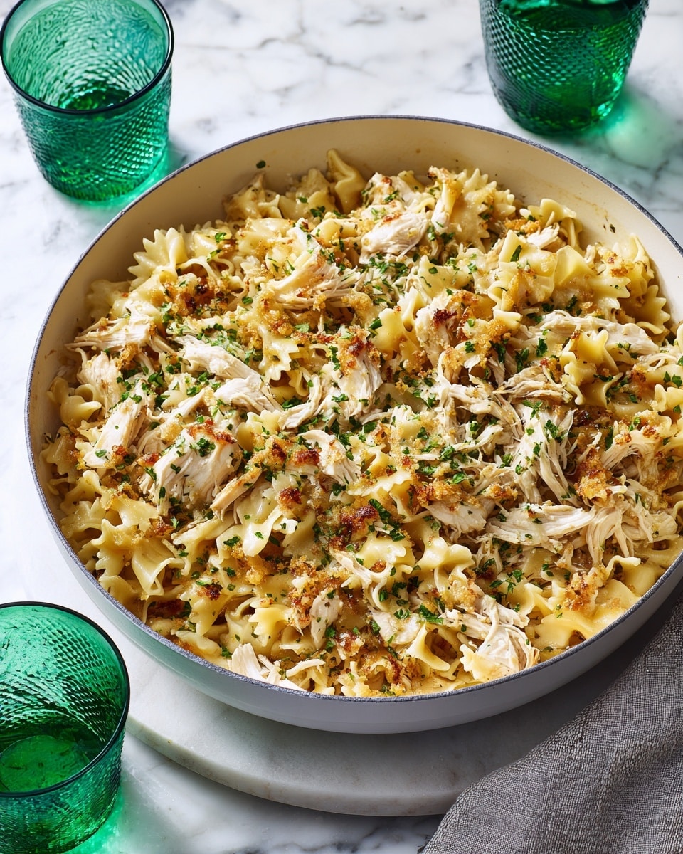 A white pan filled with a dish made of light brown toasted pasta mixed with shredded white chicken pieces, topped with small green herb sprinkles evenly spread across the surface. The pasta has a soft texture with a slightly crispy look in some places, sitting on a white marbled surface. Two green-tinted glasses with a textured pattern are placed near the pan on either side. Photo taken with an iphone --ar 4:5 --v 7