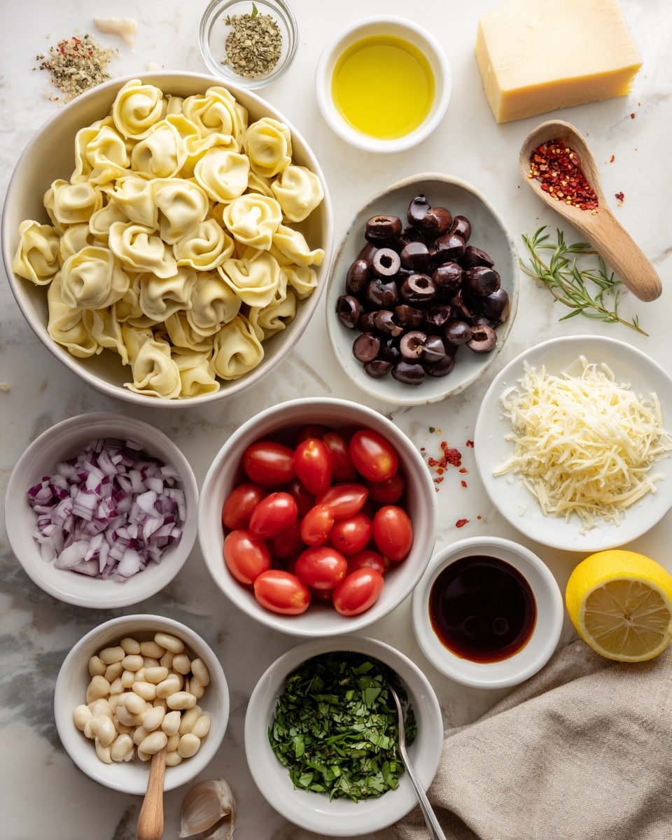 A top-down view of several white bowls and small plates arranged on a white marbled surface. The largest bowl at the bottom center is filled with pale yellow tortellini pasta. Above it, a medium white bowl is full of halved bright red cherry tomatoes. To its right, a small white dish holds black sliced olives. Another small plate to the top right contains a wedge of pale yellow cheese sitting on a pile of shredded cheese, with a small wooden spoon next to it. Other small bowls contain light yellow olive oil, creamy mustard, dark soy sauce, chopped red onions, diced red peppers, and white beans. Two small white dishes hold green chopped herbs and mixed dried herbs with red flakes. A halved lemon is on a folded beige cloth to the right. Some herbs are scattered slightly on the surface. Photo taken with an iphone --ar 4:5 --v 7