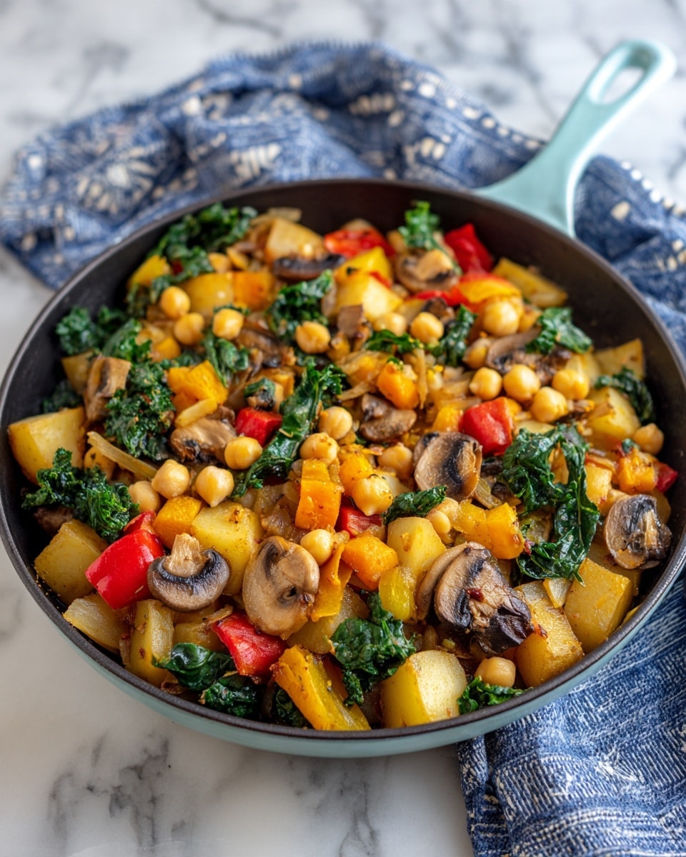 The image shows a black skillet full of cooked vegetables and chickpeas on a white marbled surface with a blue and white cloth in the background. The dish has several layers: the base is light brown diced potatoes, mixed with yellow and orange chunks of squash or bell pepper. Scattered among these are whole round chickpeas with a creamy color, dark brown sliced mushrooms, bright green kale leaves, and red bell pepper pieces. The vegetables have a soft, cooked texture, and the skillet handle is light blue. photo taken with an iphone --ar 4:5 --v 7