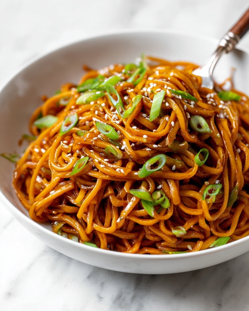 A white bowl filled with a heap of orange-brown noodles mixed with sliced green onions, sprinkled on top with small white sesame seeds. The noodles appear glossy and well-coated with sauce. A silver fork with a wooden handle is stuck upright in the noodles. The bowl rests on a white marbled surface. photo taken with an iphone --ar 4:5 --v 7