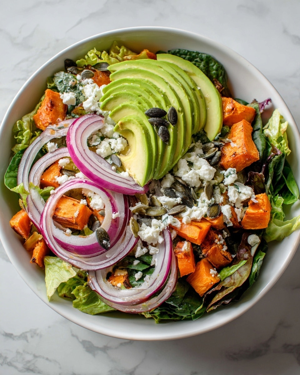 A fresh salad served in a white bowl shows many colorful layers. The base is green lettuce leaves mixed with some dark spinach. On top, there are slices of bright green avocado, peeled and fanned out nicely. Small chunks of orange roasted sweet potato are scattered evenly. Thin slices of deep red onion add sharp color. There is also white crumbled cheese sprinkled across everything. A few dark pumpkin seeds are placed on the salad, giving it a bit of texture. The bowl sits on a white marbled surface. photo taken with an iphone --ar 4:5 --v 7