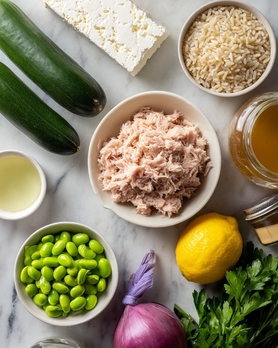 A variety of fresh ingredients are arranged on a white marbled surface. In the center is a white bowl filled with light pink, shredded tuna. Above it to the left are two dark green cucumbers placed side by side. Nearby is a block of white feta cheese with some texture holes. To the right is a white bowl filled with light brown uncooked rice grains. Below the cheese is a small white cup containing a light amber liquid. There is a bright yellow lemon to the right of the cup. Near the lemon is a small glass jar with a darker amber liquid. Below the tuna bowl is a white bowl full of bright green edamame beans. Next to it is a small red onion with smooth, shiny skin. On the bottom right, a bunch of fresh green parsley is tied with a purple band. photo taken with an iphone --ar 4:5 --v 7