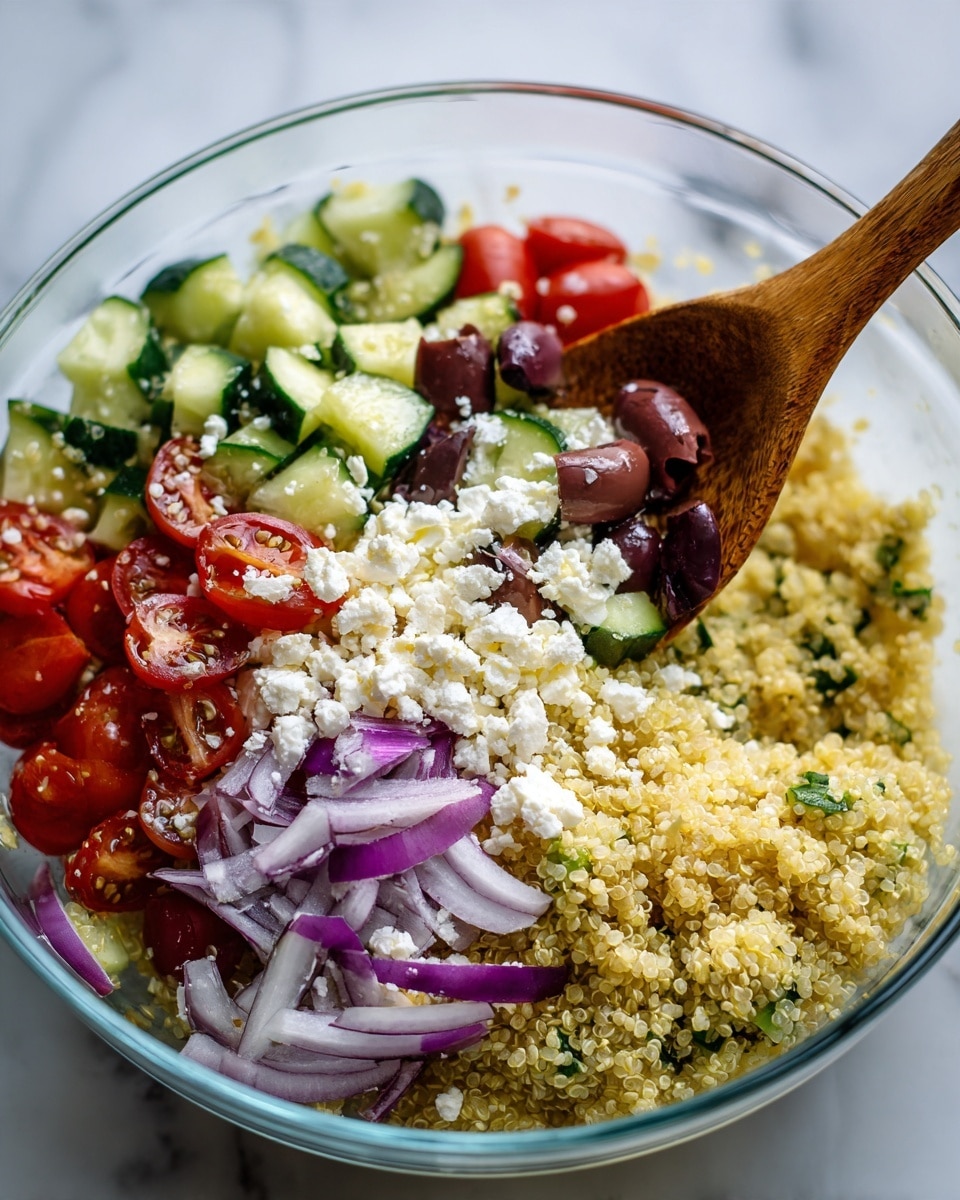 A clear bowl filled with a colorful quinoa salad on a white marbled surface. The salad has three main layers: the bottom layer is fluffy, pale yellow quinoa, the middle layer includes light green cucumber chunks and thin slices of purple-red onion, and the top layer is dotted with halved bright red cherry tomatoes, crumbled white feta cheese, and slices of dark purple olives. A wooden spoon is scooping some of the salad from the right side of the bowl. Photo taken with an iphone --ar 4:5 --v 7