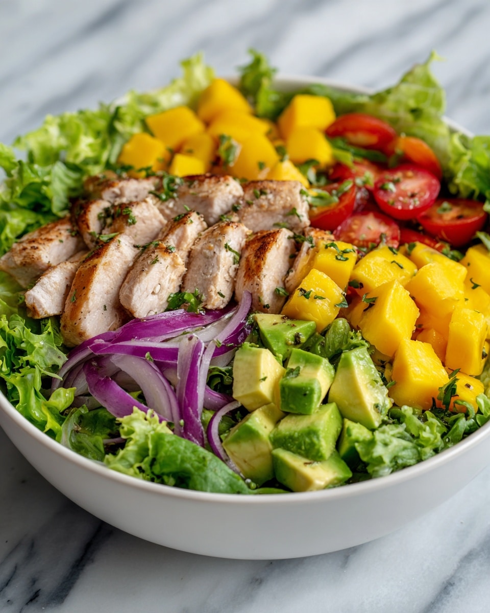 The image shows a colorful salad in a white bowl placed on a white marbled surface. The salad has several layers: the base is made of fresh green lettuce leaves with a crinkly texture, mixed with chunks of bright green avocado with smooth, creamy texture, and cubes of yellow mango that add a pop of color. There are slices of grilled chicken with a light brown, slightly crispy outer layer on top of the greens. Scattered around are halved small red cherry tomatoes with shiny skins and thin slices of light purple red onion. Some green herbs are sprinkled over the salad, giving it a fresh look. The overall salad has a mix of bright green, yellow, red, and light brown colors. photo taken with an iphone --ar 4:5 --v 7