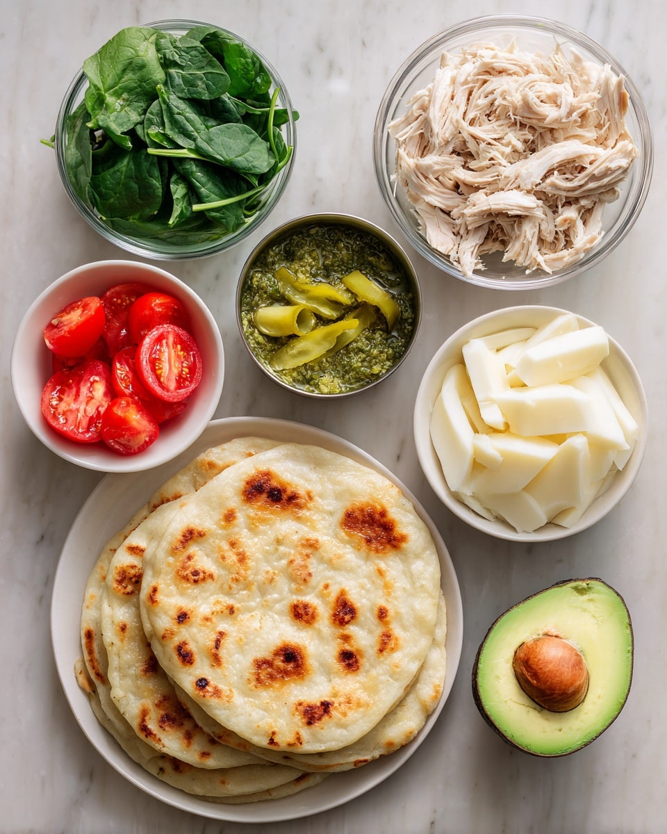 A top-down view shows an arrangement of flatbread on a white plate on the right side with a beige, lightly toasted color and a textured surface. Surrounding it on a white marbled background are clear glass bowls filled with shredded pale beige chicken, sliced creamy white mozzarella cheese, and green pesto sauce with an oily texture. A small metal container in the center holds bright yellow-green sliced pickled peppers. A white bowl on the left holds fresh dark green spinach leaves with visible veins, and another white bowl below it contains three thick, red tomato slices showing their juicy interior. At the bottom right corner is a halved avocado with bright green flesh and a large brown seed. All items are arranged neatly with natural daylight. Photo taken with an iphone --ar 4:5 --v 7